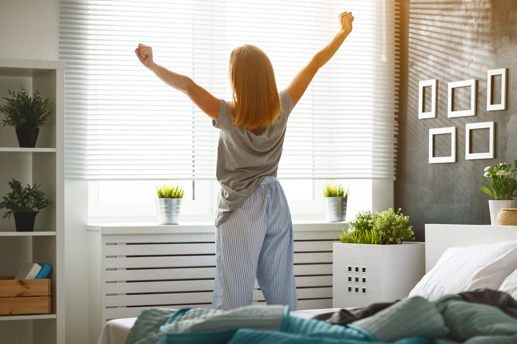 Woman stretching by window with auto blinds