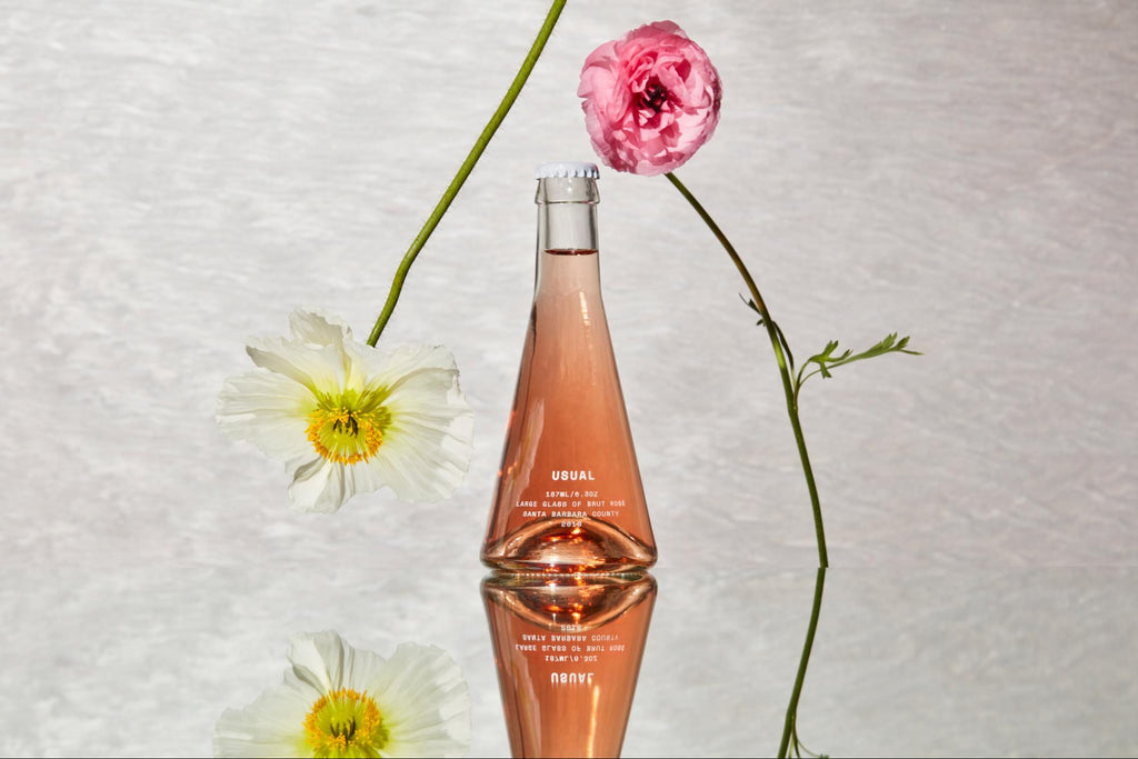 Rose wine with two flowers leaning on bottle