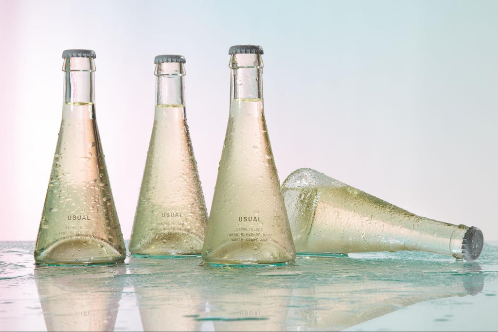 Four Usual Brut bottles on a glass surface