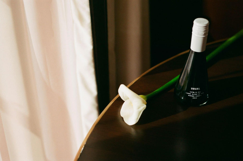 bottle of red wine from Usual Wines with a white rose on the table