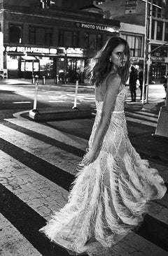 Woman crossing the street in a feathered evening dress