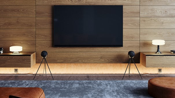 Deux haut-parleurs Devialet Phantom II placés devant un écran dans un salon 