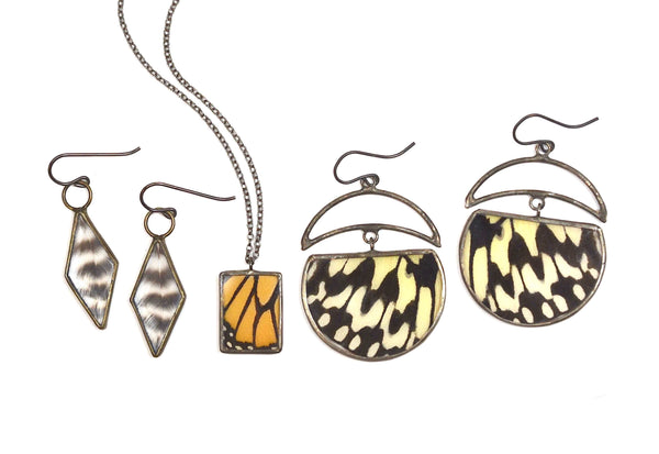 Geometric Monarch, Black and white butterflies, and striped feather jewelry arranged on a white background.