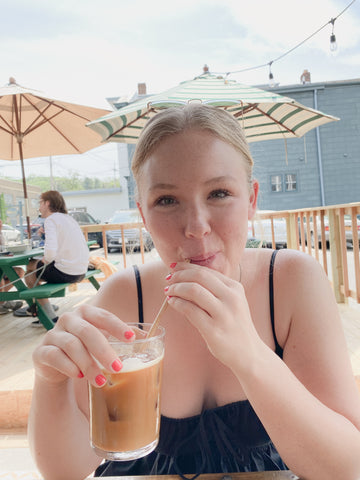 girl in black dress drinking iced coffee