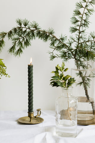 green taper candle with christmas greenery