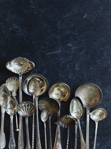 silver ladles on black background