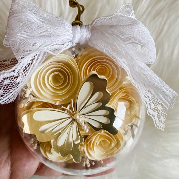 image of golden butterfly with hand-rolled flowers inside an ornament