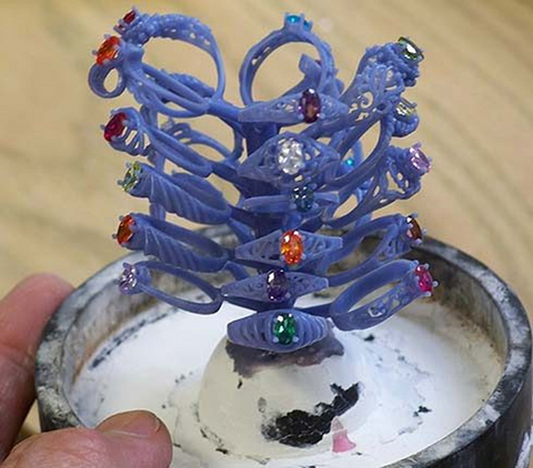 Multiple wax models attached to a “tree” of sprues ready for investment and showing the desired placement of gemstones in the final settings (gemstones are removed before investment); Image: G.n.W. Designs