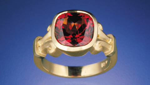 A ring featuring a faceted red garnet gemstone