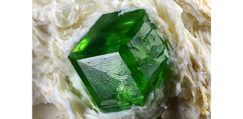 An emerald green demantoid garnet crystal in matrix of asbestos from Lombardy, Italy. Image: Mindat/ Chinellato Matteo