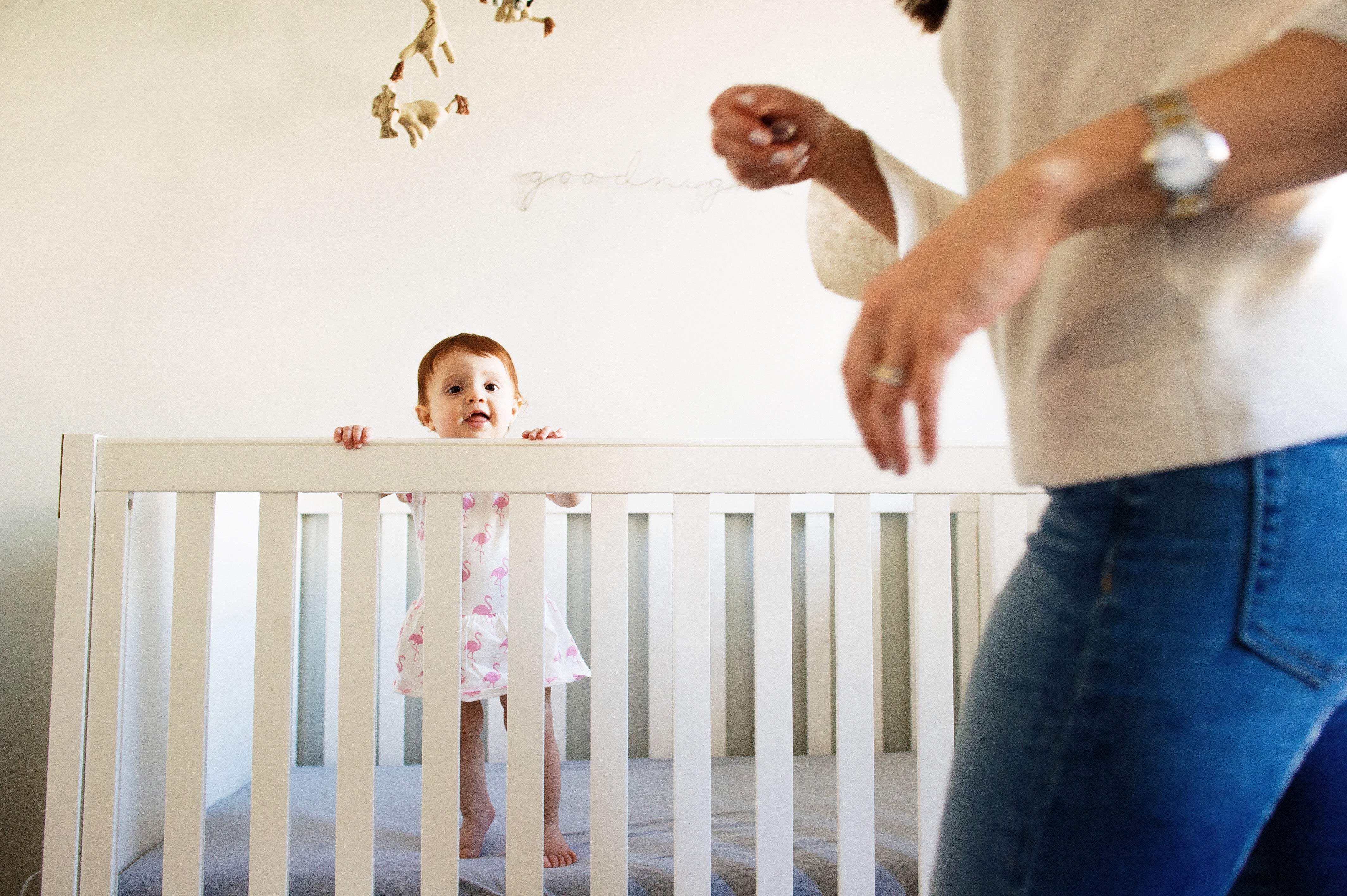 Baby in crib with mom walking by