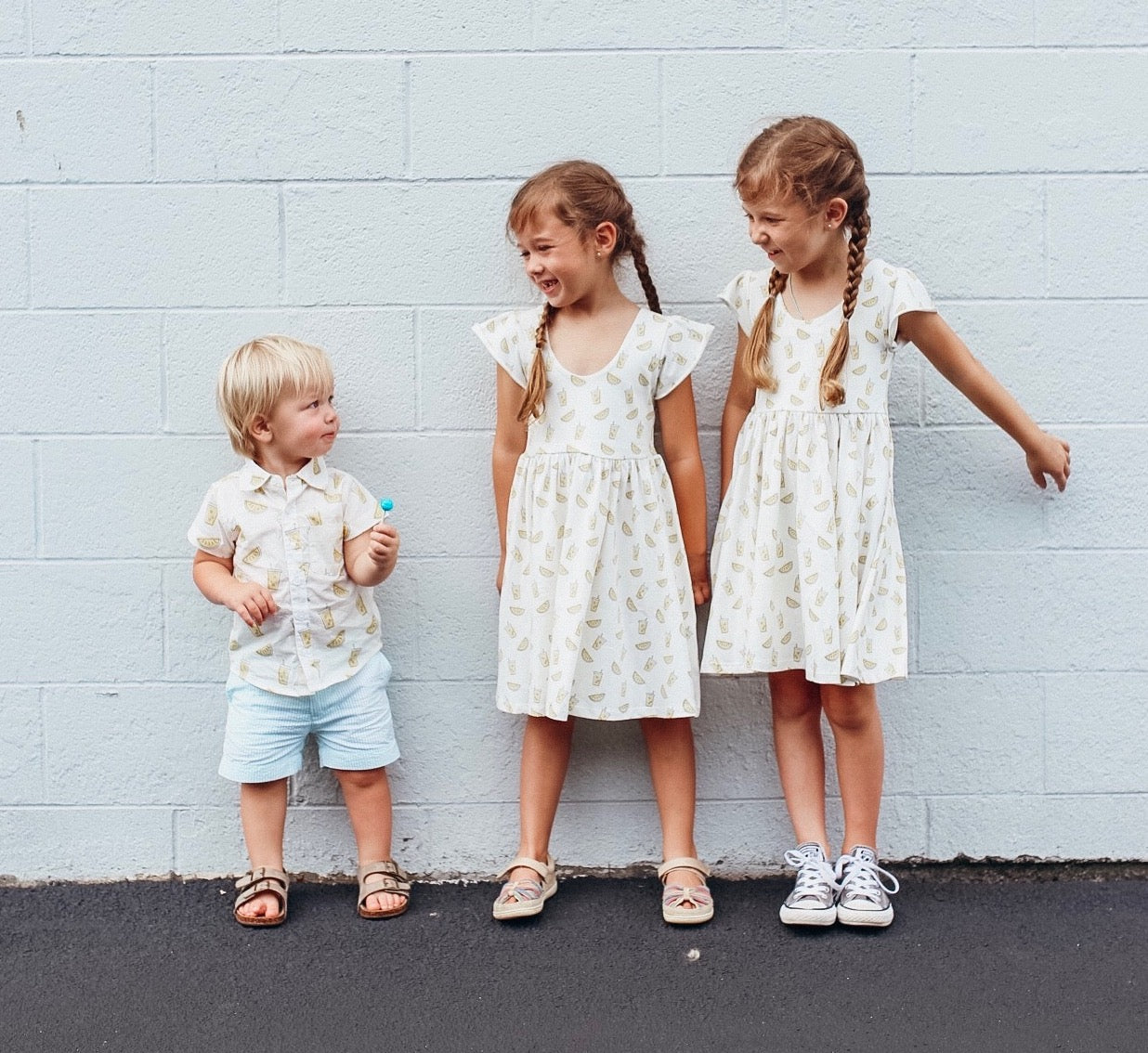 Two girls and one toddler boy in Lemonade Print outfits 