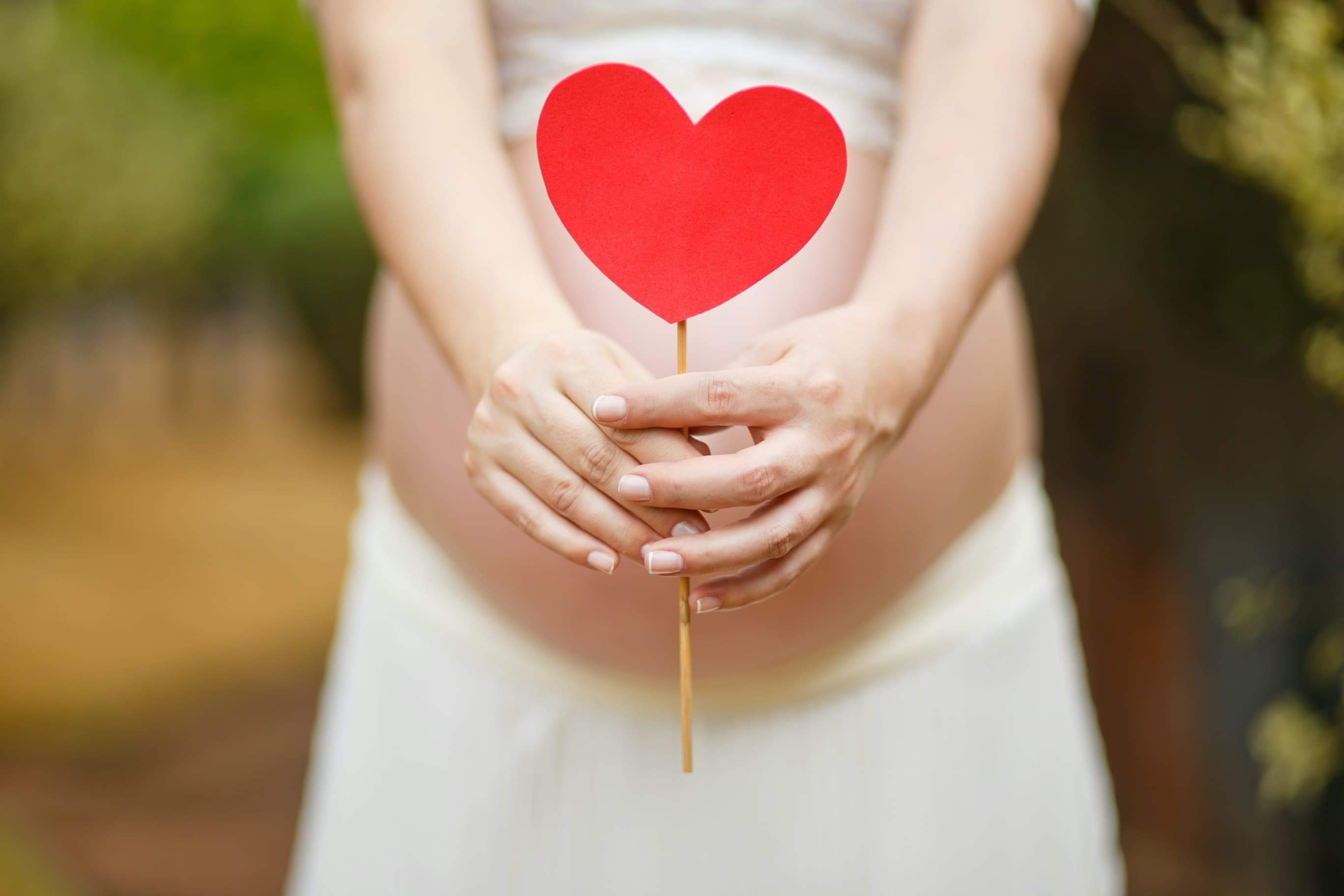Pregnant woman holding a cut-out image of a heart