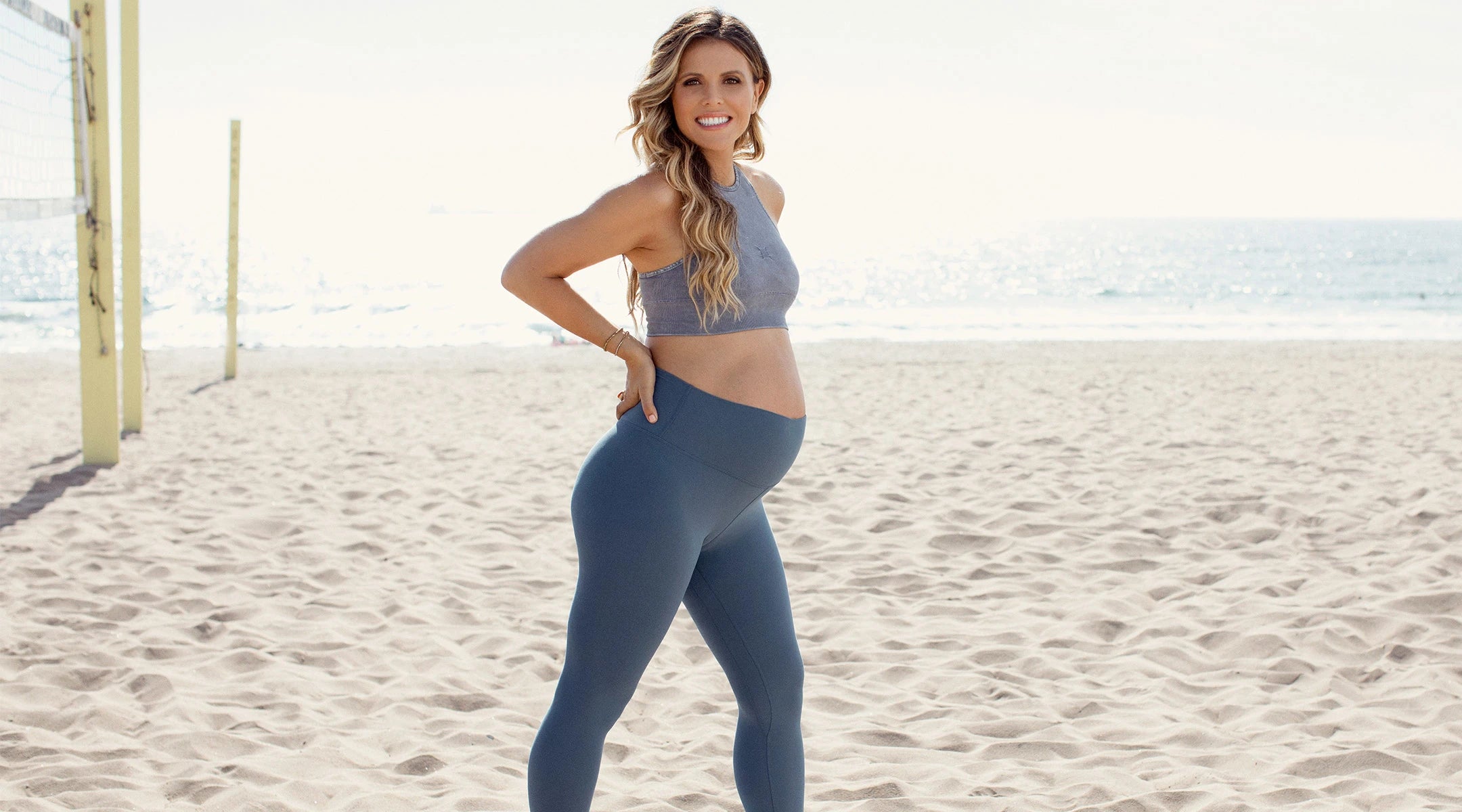 Young pregnant woman with beautiful healthy body holding dumbbells and mat