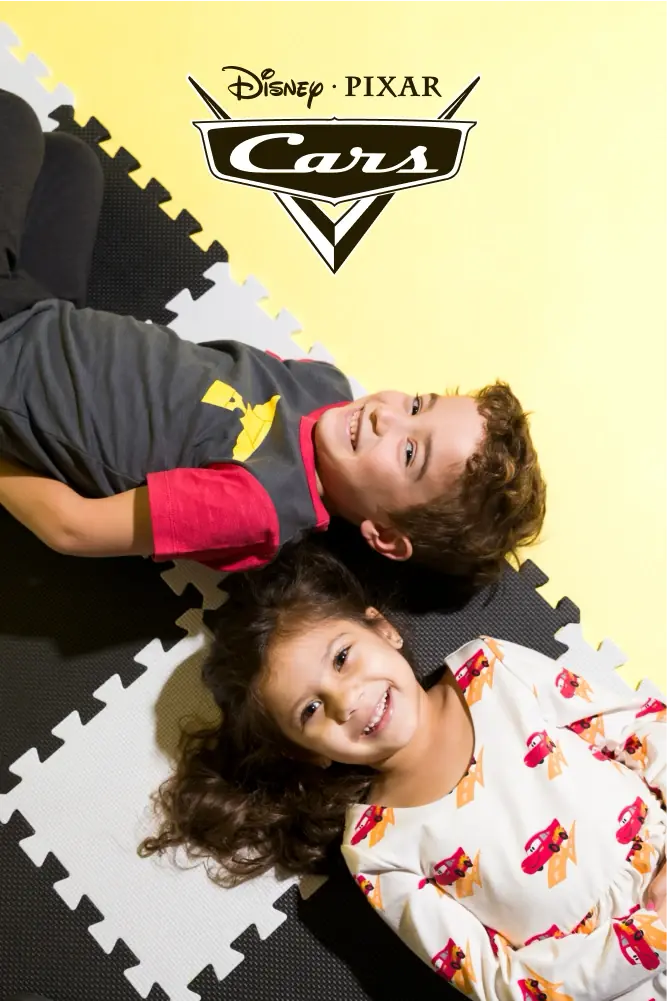 Toddlers wearing Disney Pixar Cars print clothing against yellow background