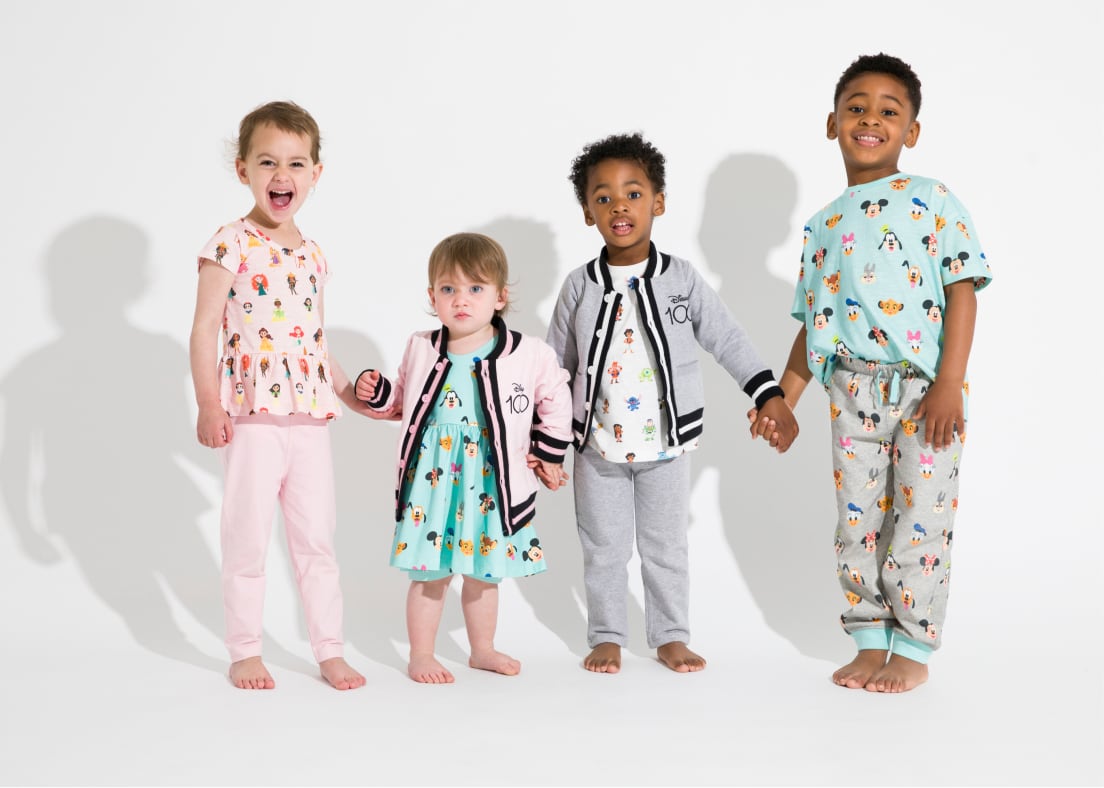 Group of standing kids wearing Disney 100 print clothing