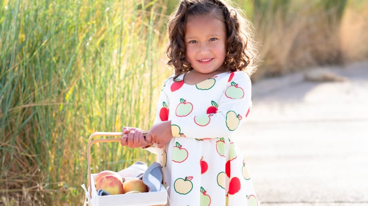 Toddler girl with basket of apples wearing Fall Apples print dress