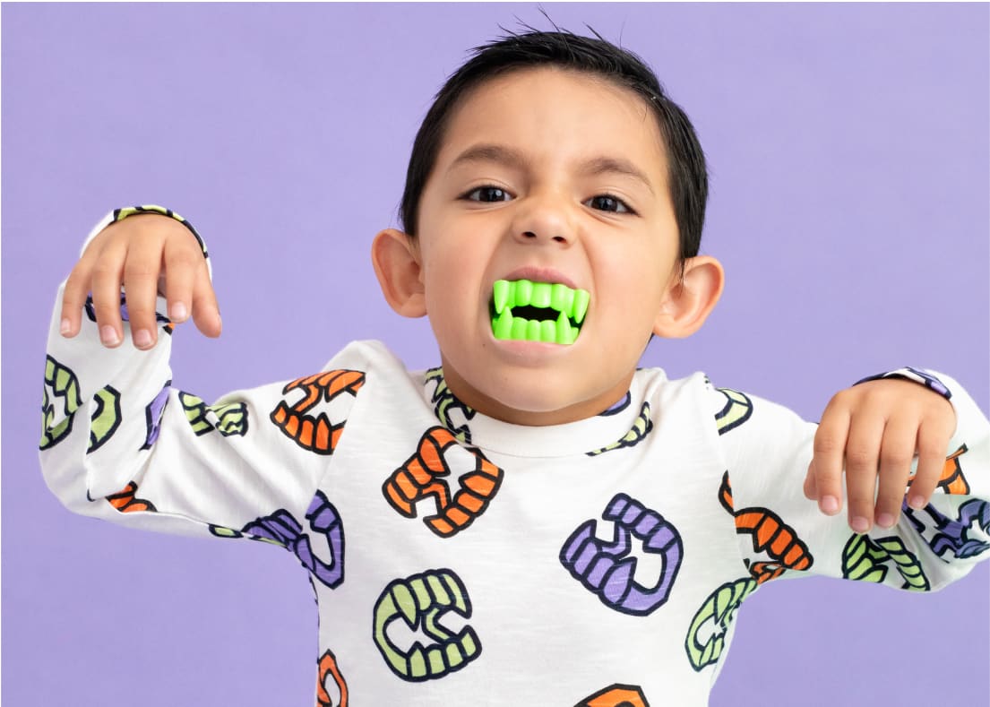 Toddler boy with fake glow-in-the-dark teeth wearing Vampire Teeth print clothing