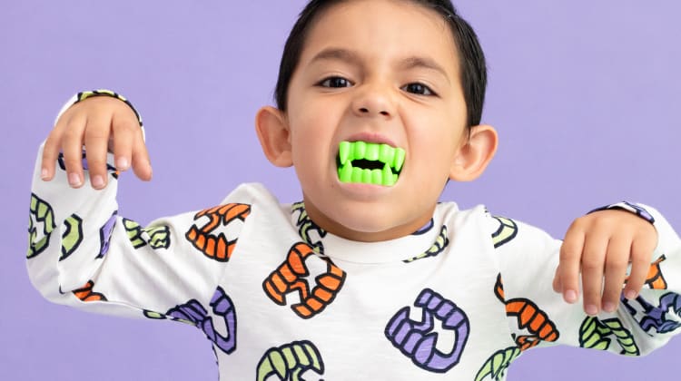Toddler boy with fake glow-in-the-dark teeth wearing Vampire Teeth print clothing
