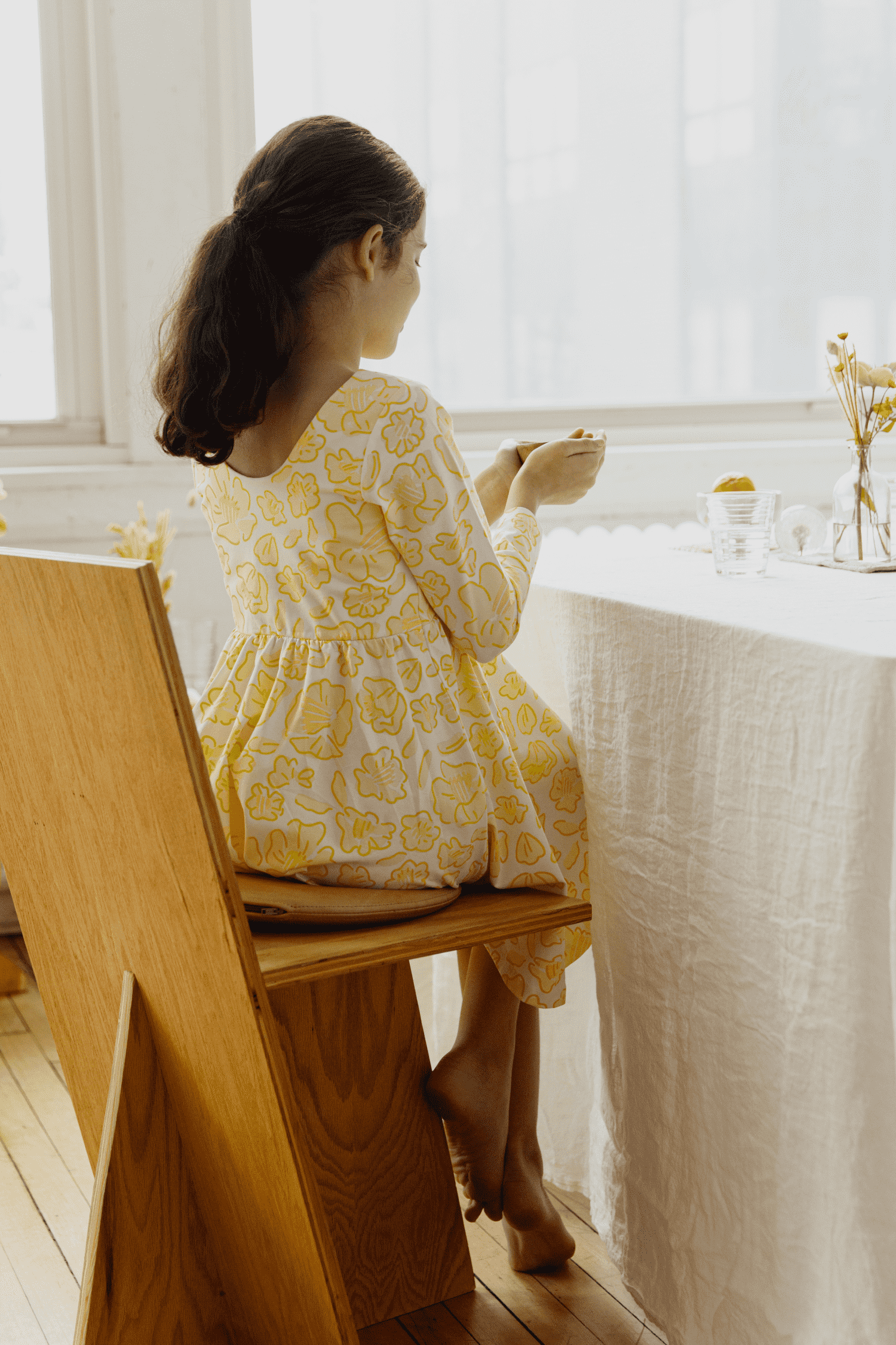 Bella sitting at table with neutral fabric background