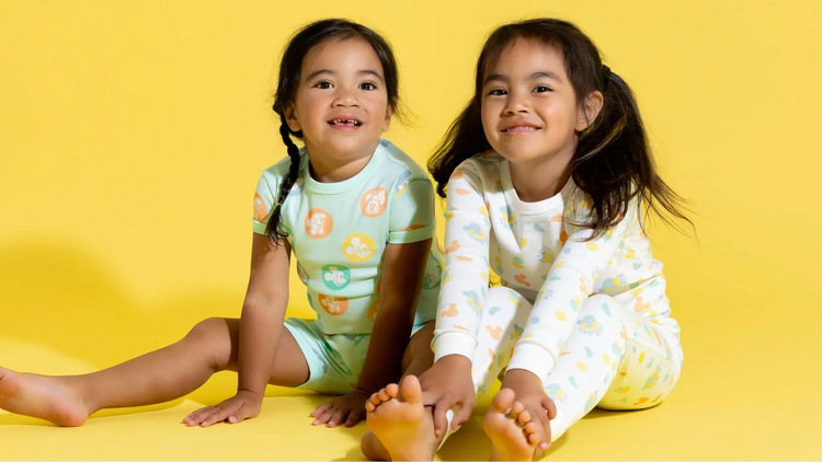 Kid in Disney Groovy Collection print pajamas against yellow background