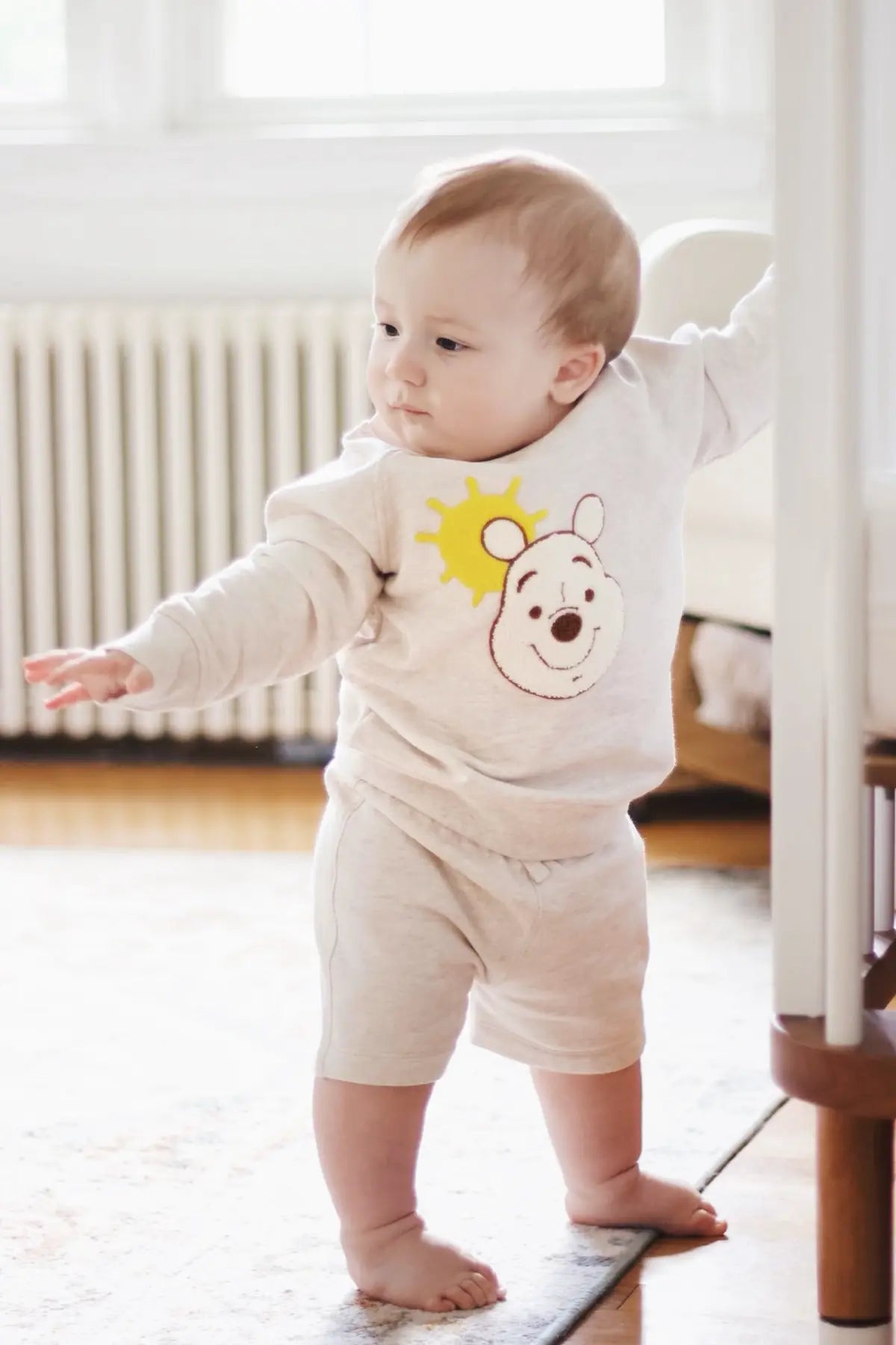 Baby taking steps in Winnie The Pooh romper