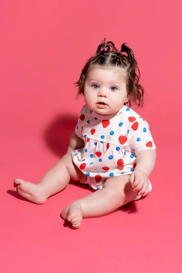 Baby girl in Red, White & Cute print Shortie Bubble Romper against red background