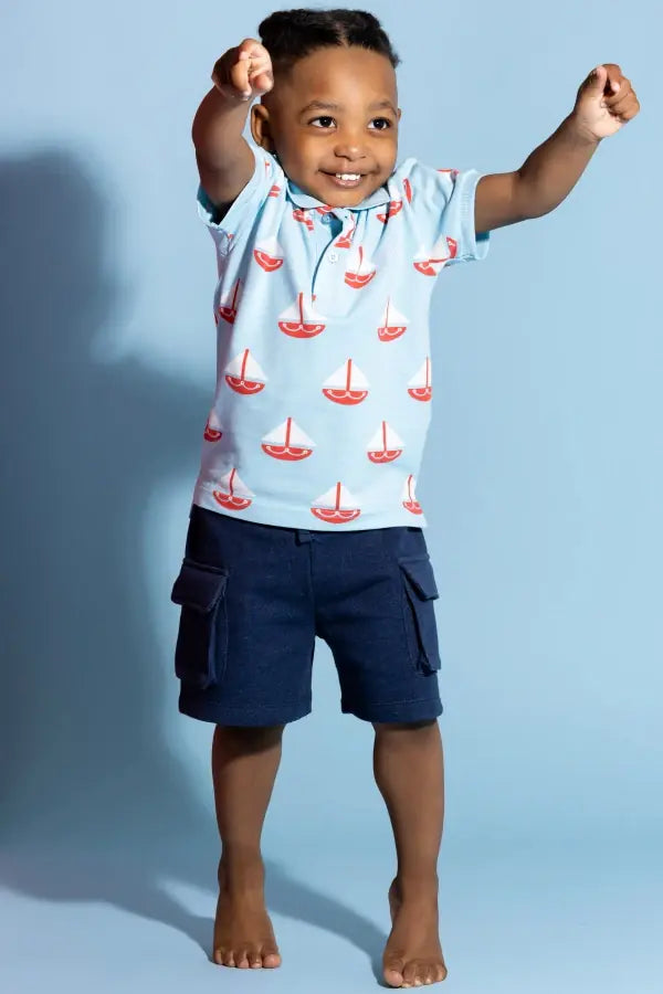 Boy in Summer Sail print polo against blue background