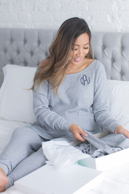 Mom in embroidered loungewear opening gift on bed