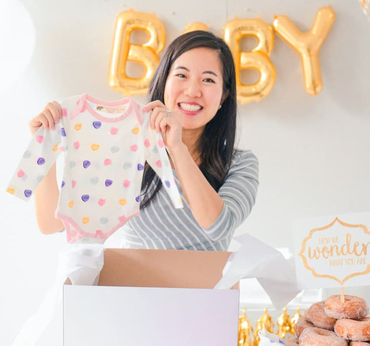 Woman holding up romper at baby shower