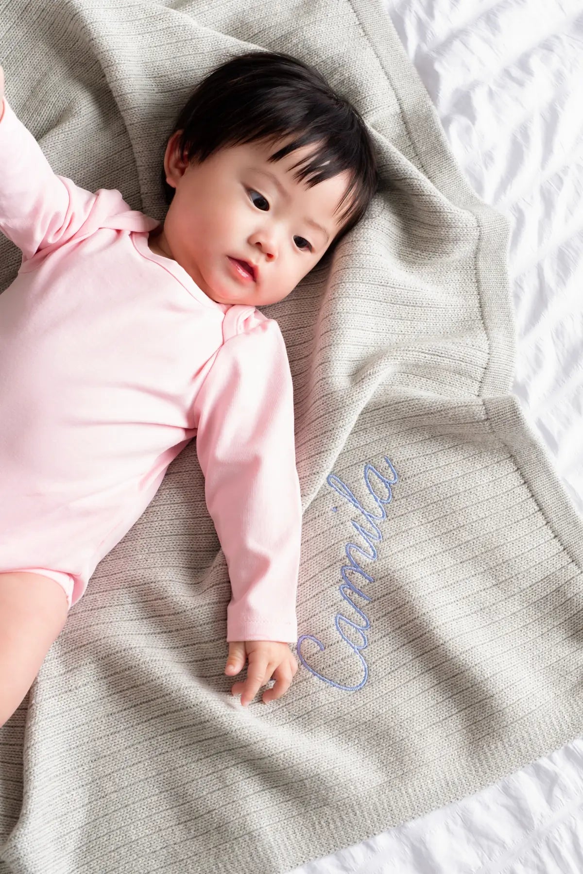 Baby in pink romper on bed