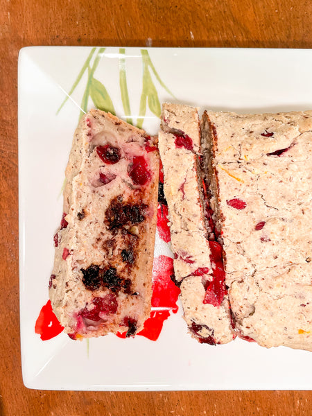 Sliced Cranberry & Orange Loaf on white plate on wooden table