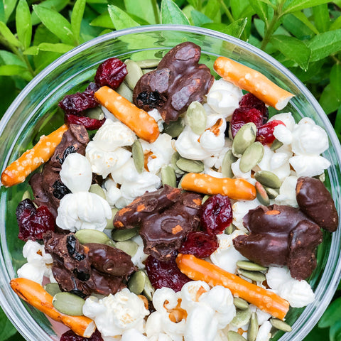 bowl of freshly made popcorn with pretzels, pepitas, and sustainable snacks chocolate superfood snack on top