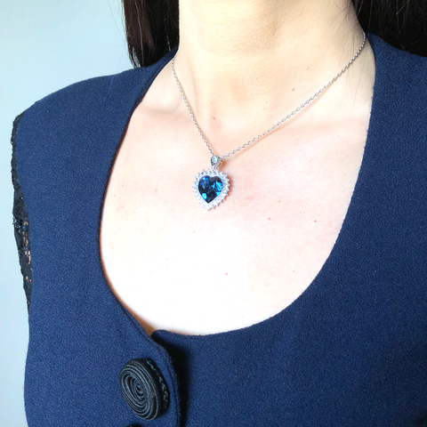 <img src="Blue heart necklace" alt="Navy blue colored crystal in heart shape with silver embellishments ">