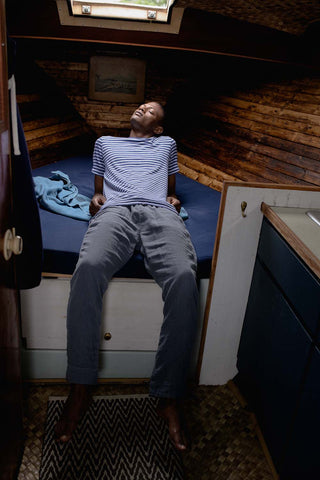 Lucas wearing cotton hem marine stripe short sleeve shirt with triple gauze easy chino, lounging on a cot inside a boat