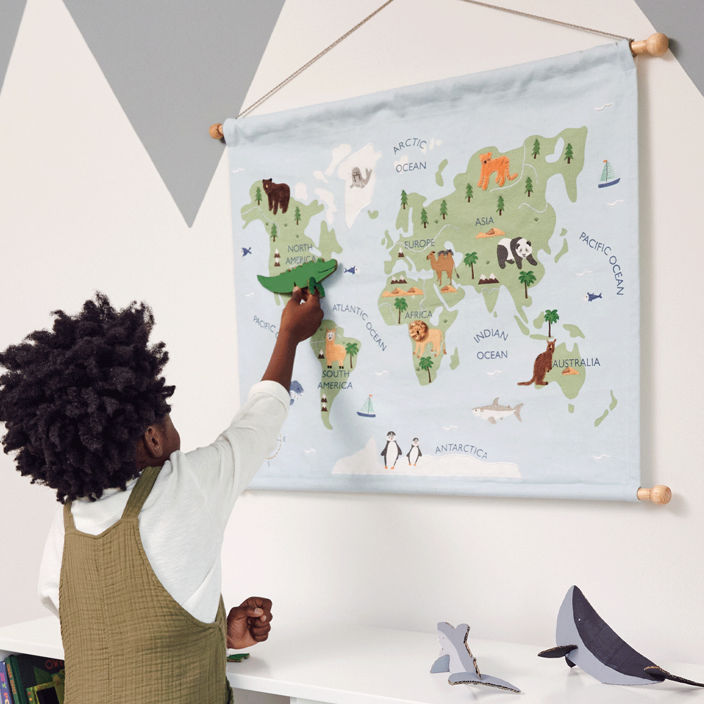 Boy pointing at around the world wall hanging