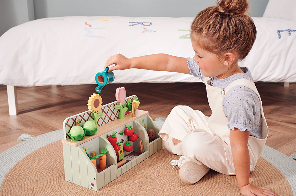 Young girl playing with wooden garden toy