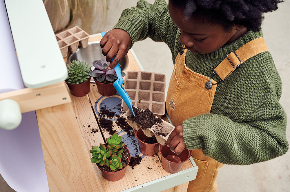 Young boy playing outside, potting plants
