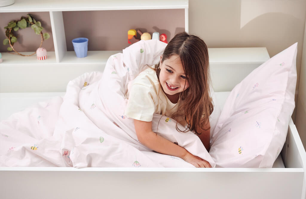 young girl wrapped in Buzzy Blooms themed duvet