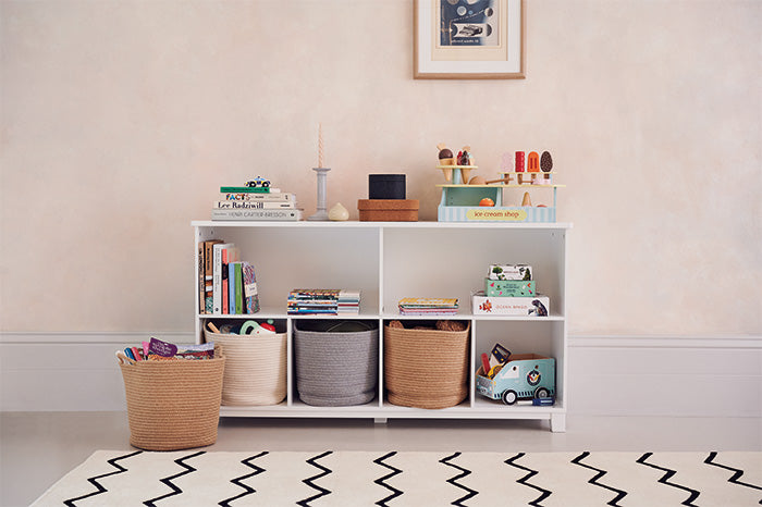 Long storage shelf filled with toys and rope storage baskets