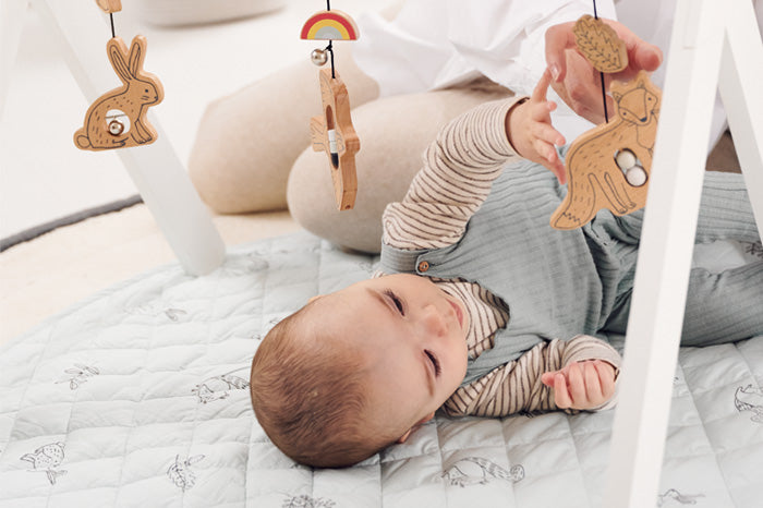 baby playing with wooden play gym
