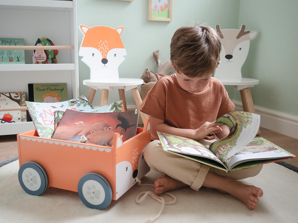 Young boy reading from book cart