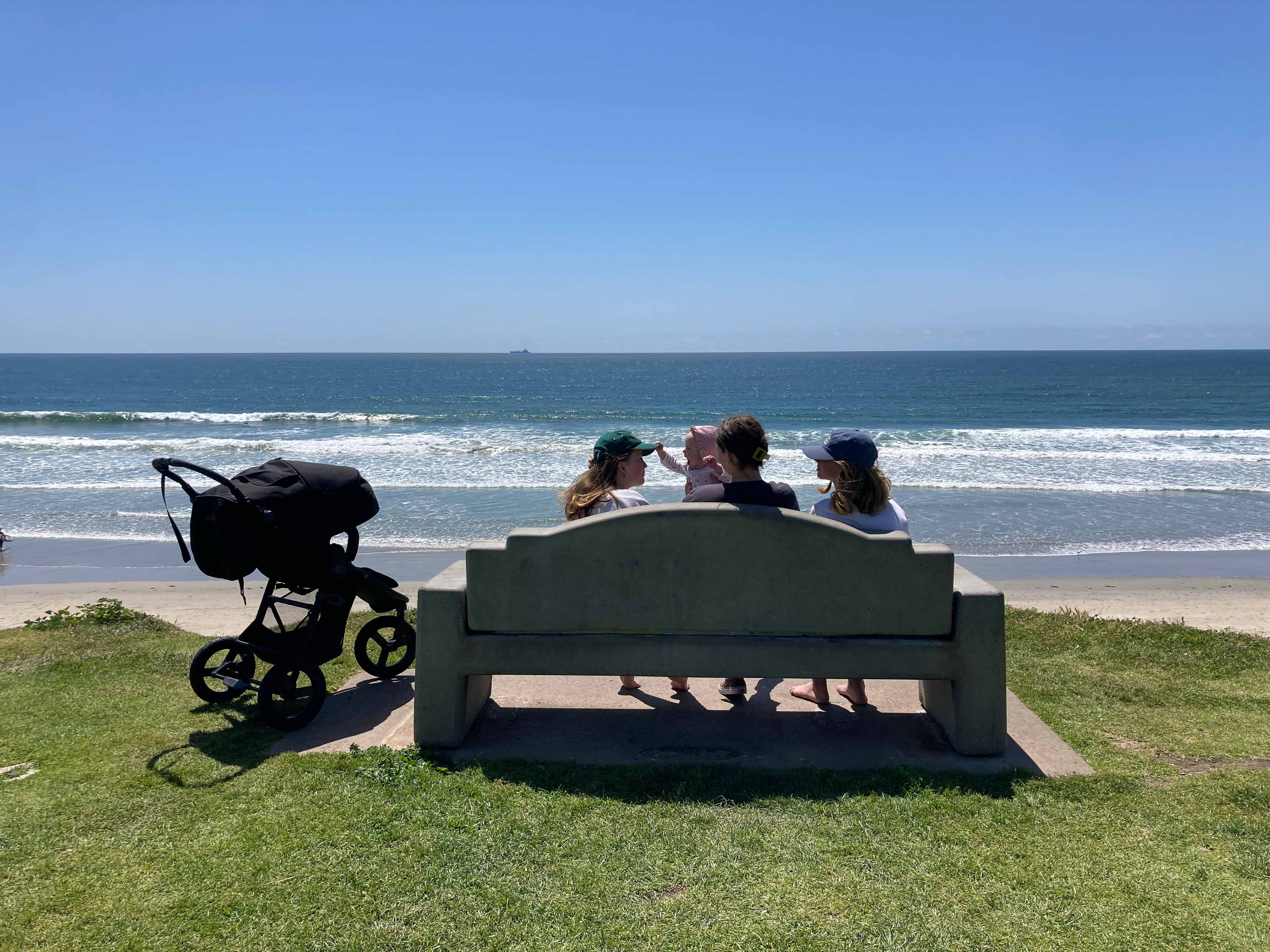 Picture of bench overlooking ocean with family sitting with bumbleride stroller parked nearby