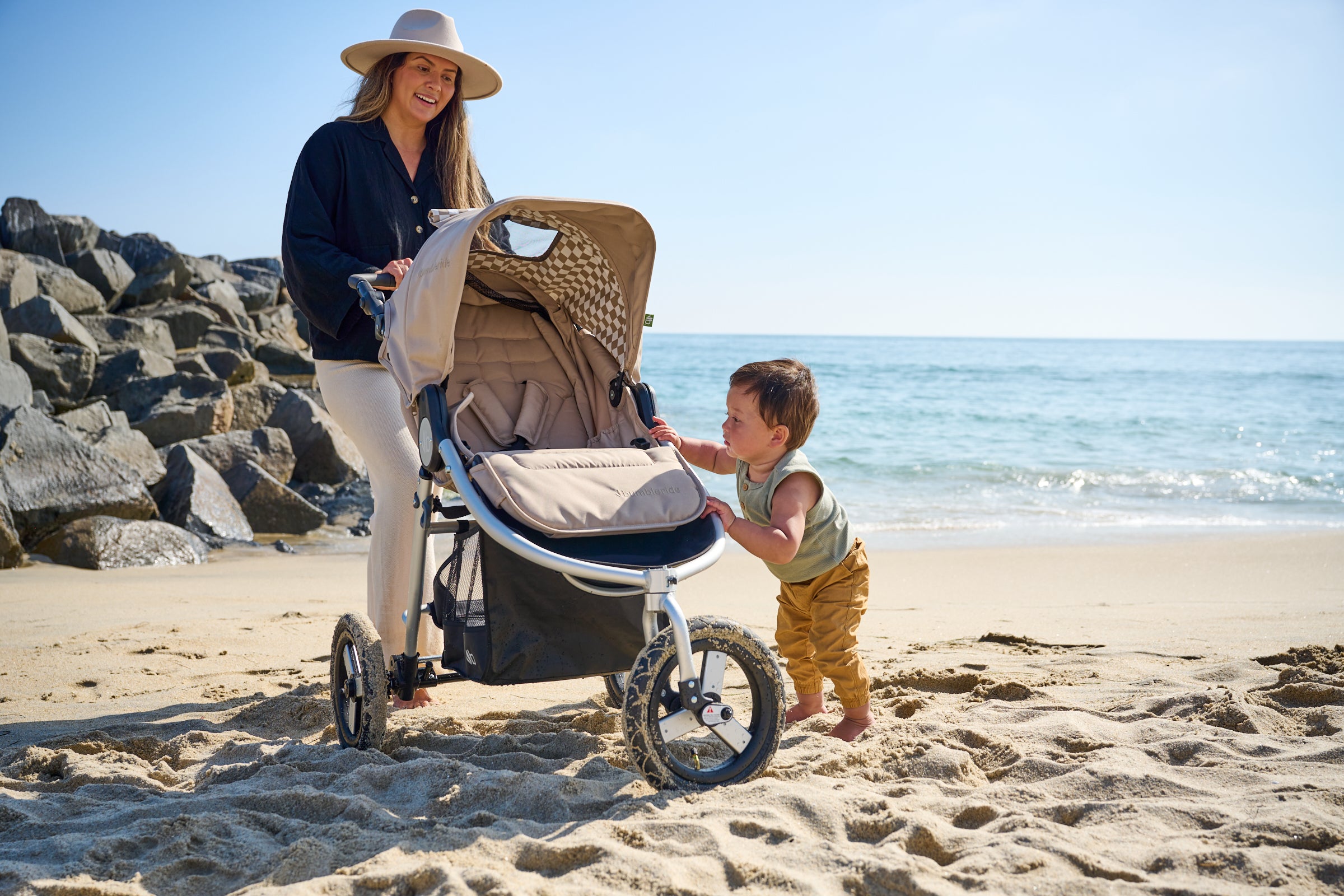 Picture of mother and son standing on sand at beach with 2022 Bumbleride Indie. New Collection.