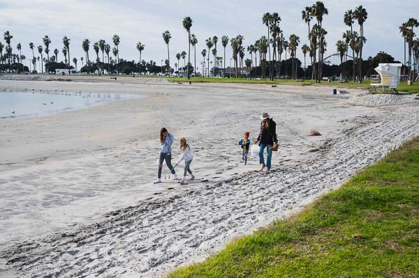 Picture of children and adults cleaning beach at mission bay next to park