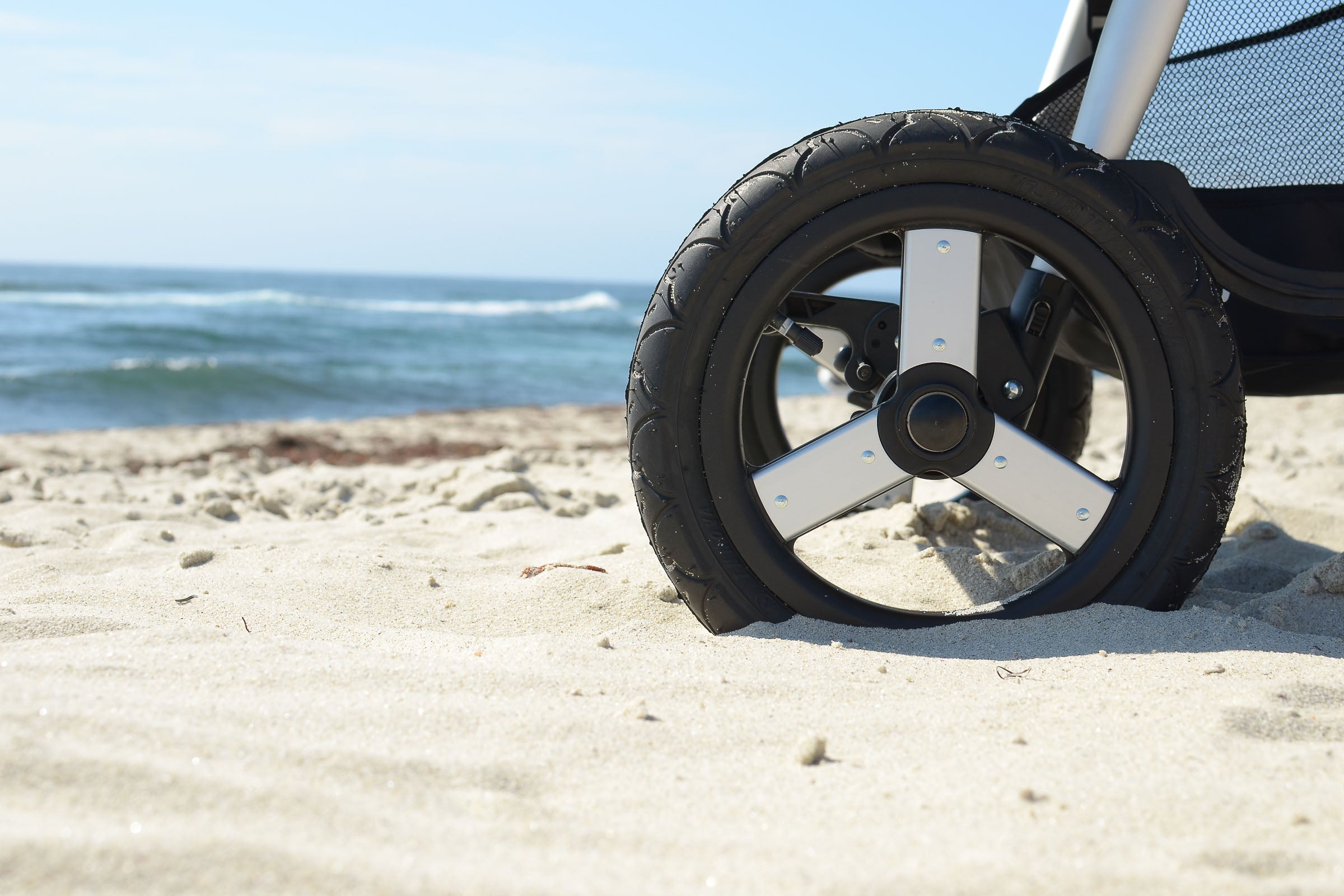 Photo of 2021 Bumbleride Indie Twin Double Stroller Wheel on beach sand with ocean in background