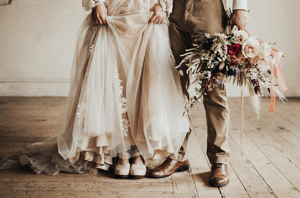 bride and groom standing together with bride wearing high heeled clog sandals in a sand-colored nubuck leather