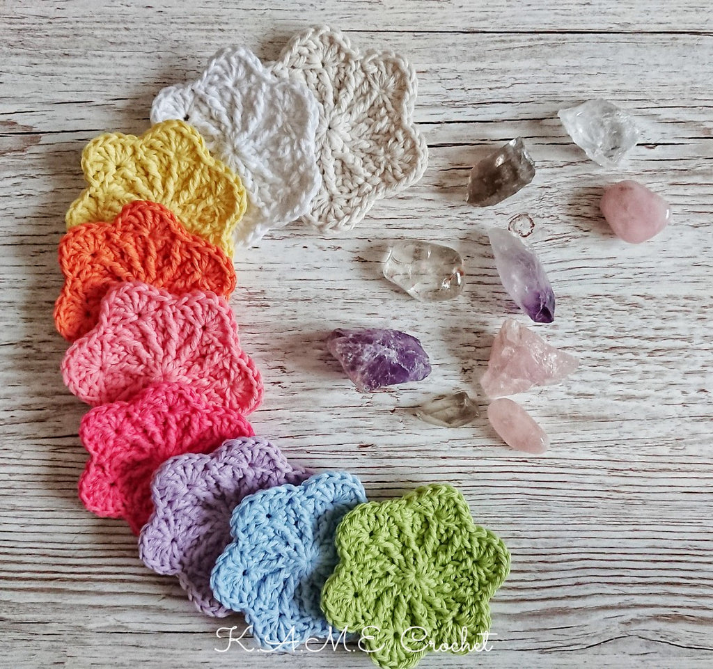 A collection of crocheted face scrubbies sits on a wood counter with a collection of crystals