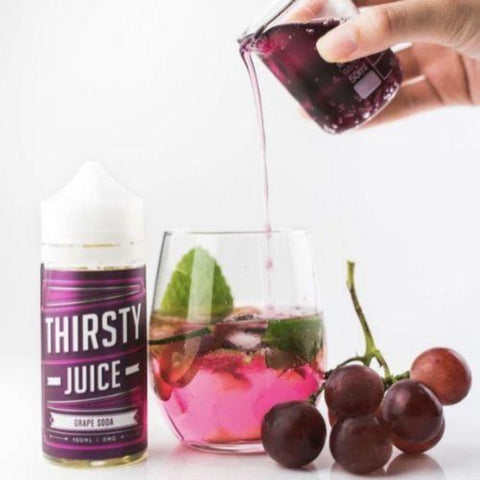 Thirsty Juice Co | Grape Soda 100ml bottle with a glass of grape juice being poured from another glass and 6 purple grapes on the vine