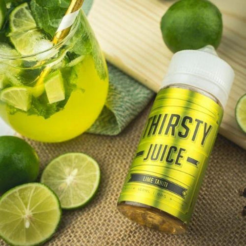 Thirsty Juice Co | Lime Tahiti 100ml bottle laying on a table with a whole lime and sliced lime and a glass of green lime juice